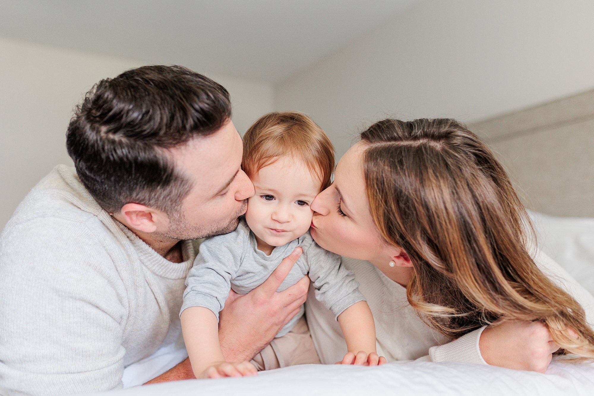 parents kiss baby boy on cheek during family phots at home with Maryland and DC family photographer 