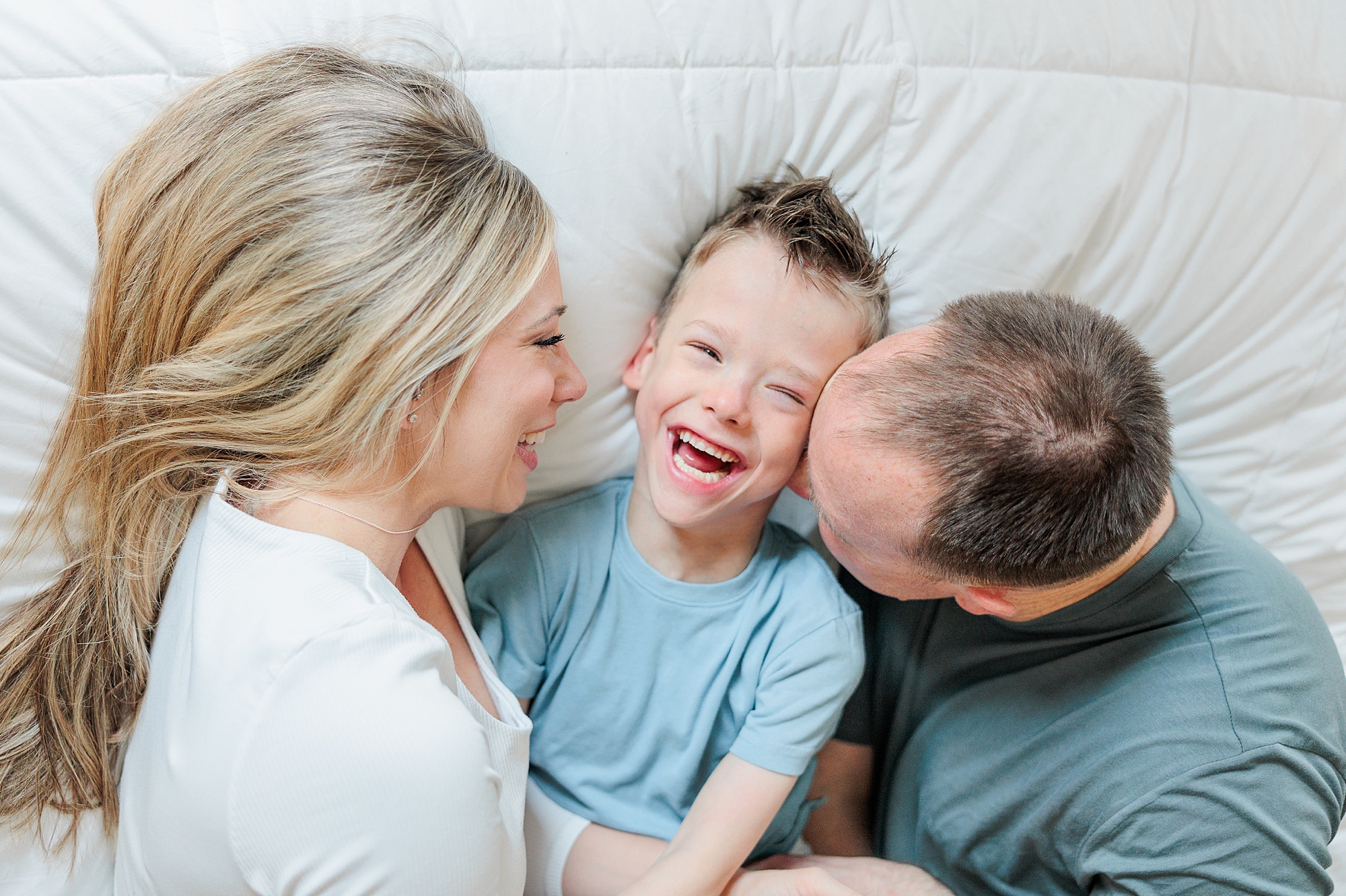 parents snuggle with son during family photos at home