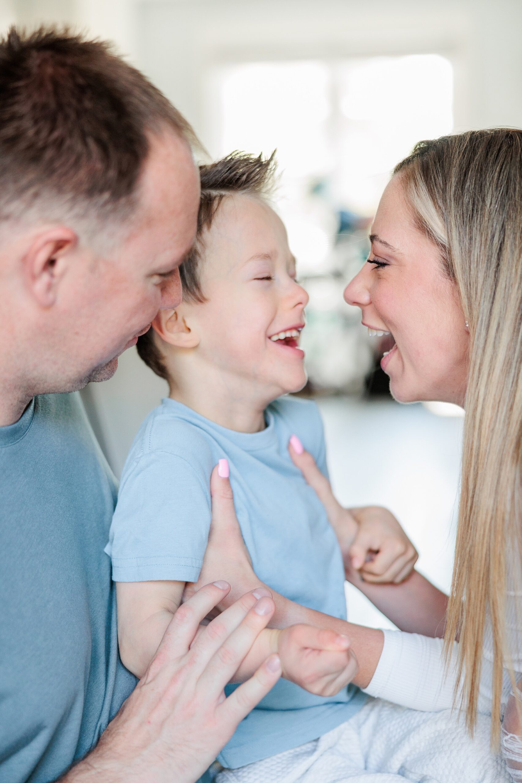 mom and dad laugh with son during family photos in Maryland home