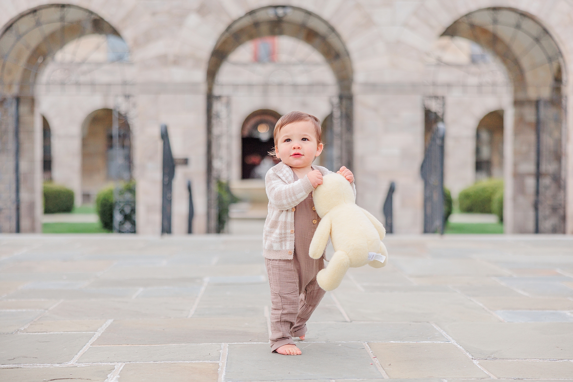 baby walks with stuffed animal and grey sweater on 