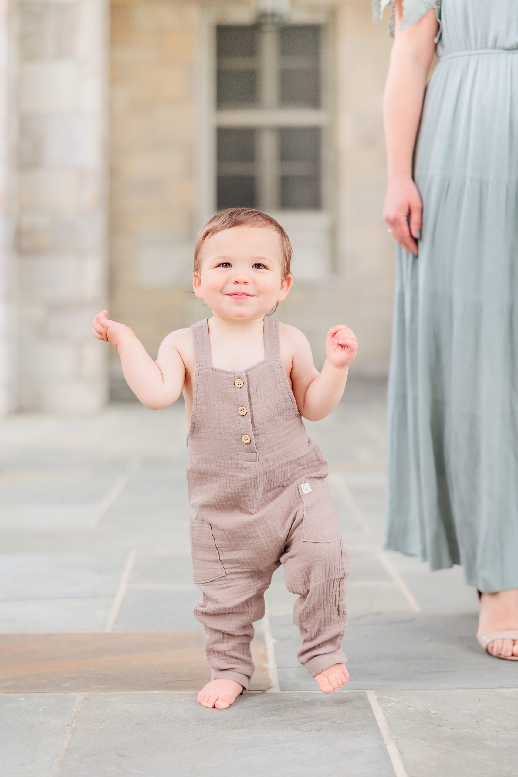 toddler in brown onesie walks beside mom during Maryland Family Session in Ellicott City 