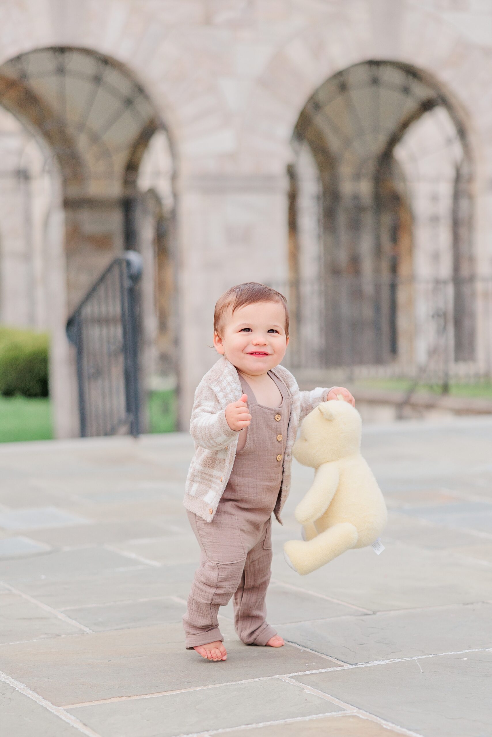 toddler laughs holding bear during family photos