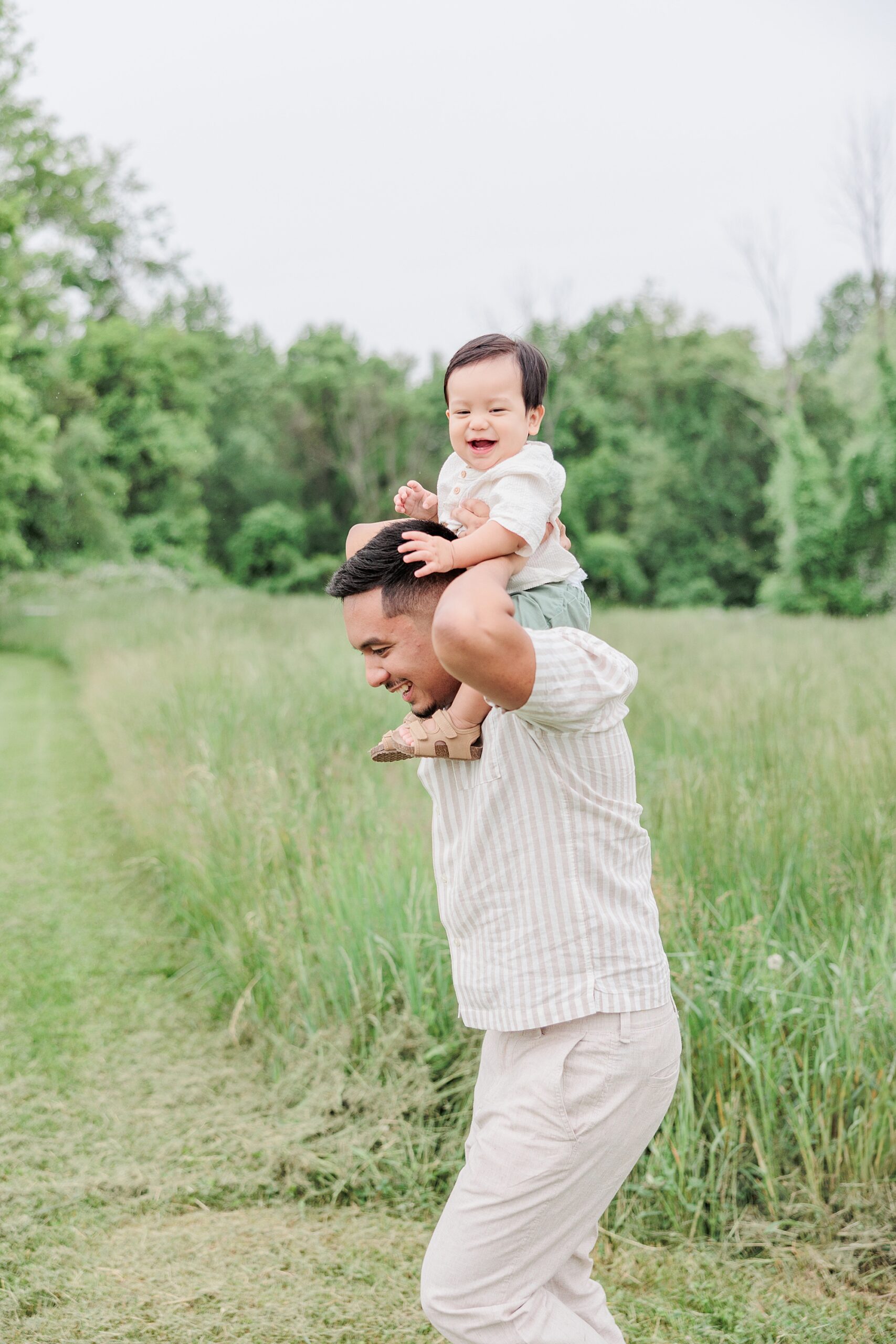 dad gives son ride on his shoulders during family photos in field of peonies