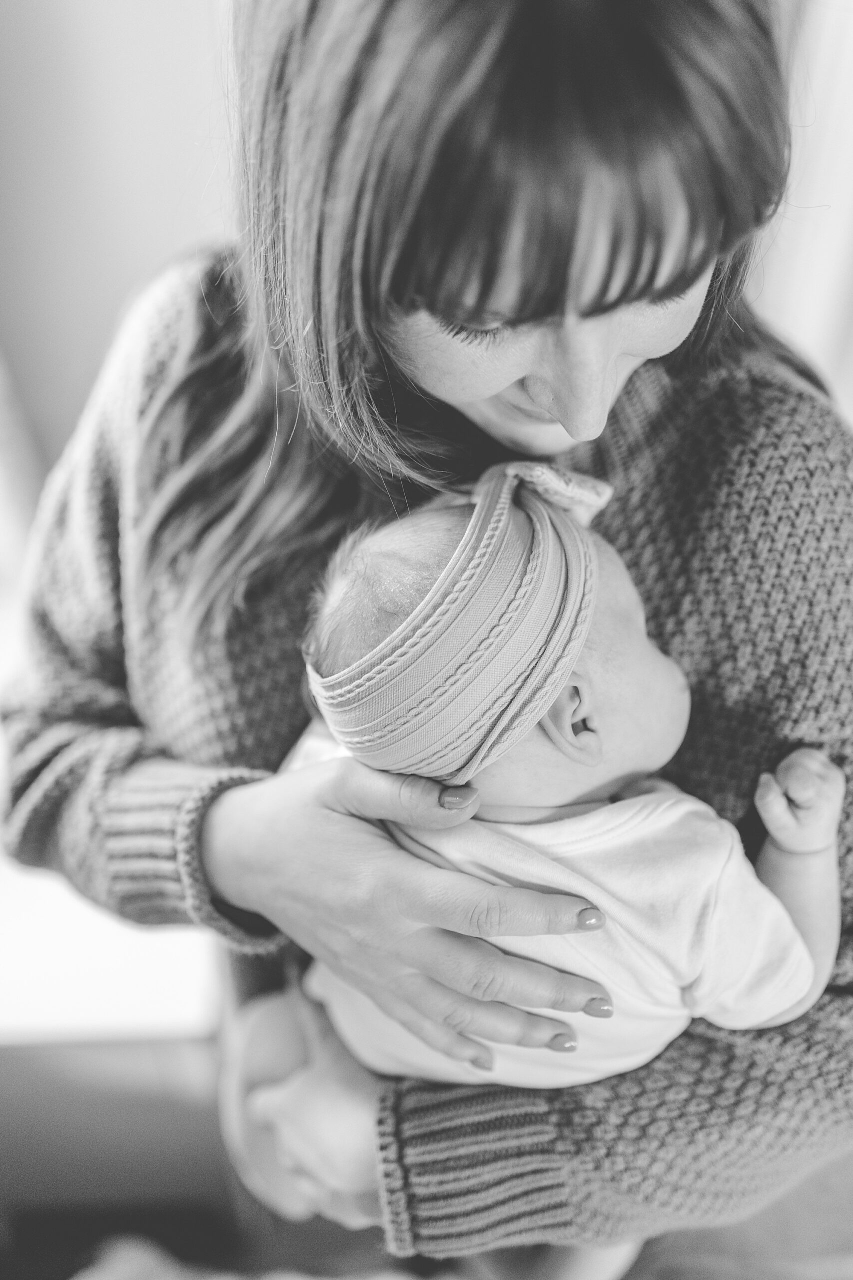 mother holds baby girl to her chest in sweater 