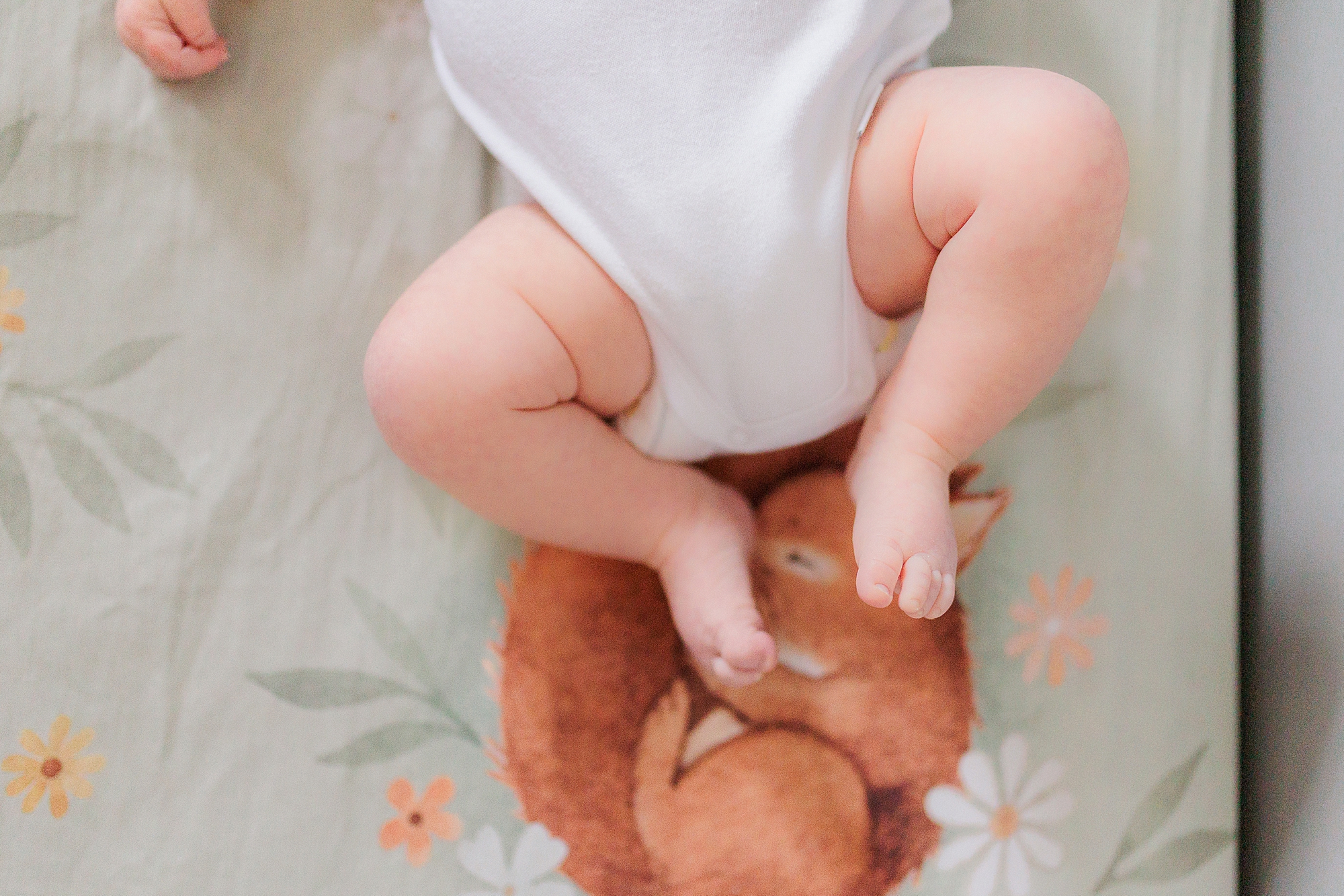 baby's chunky legs laying on floral blanket in crib