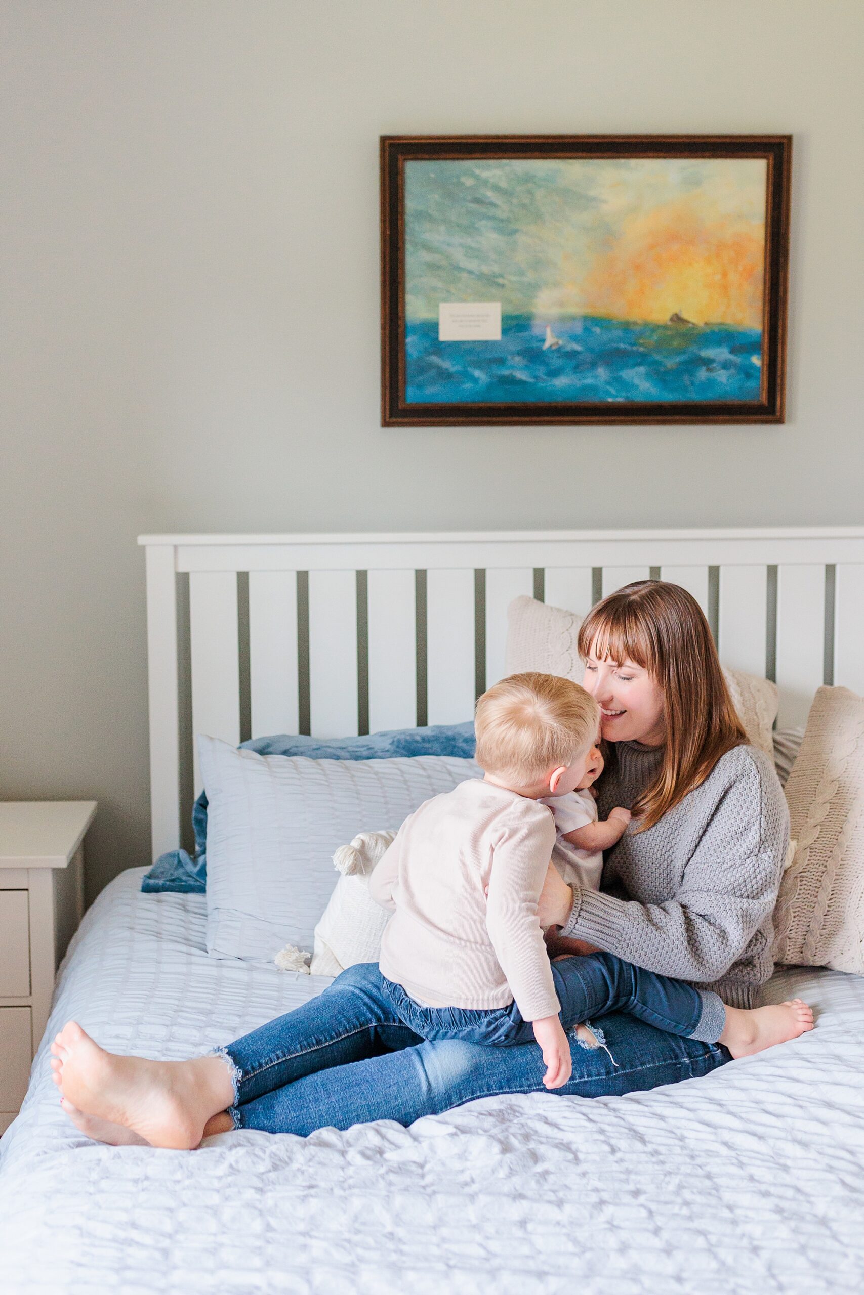 mother sits in nursery with baby and toddler on her lap