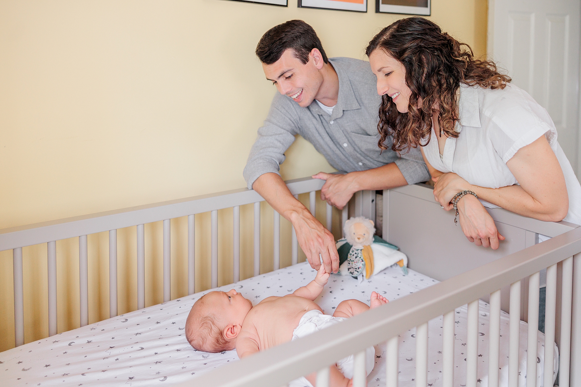 couple looks over side of crib at newborn son