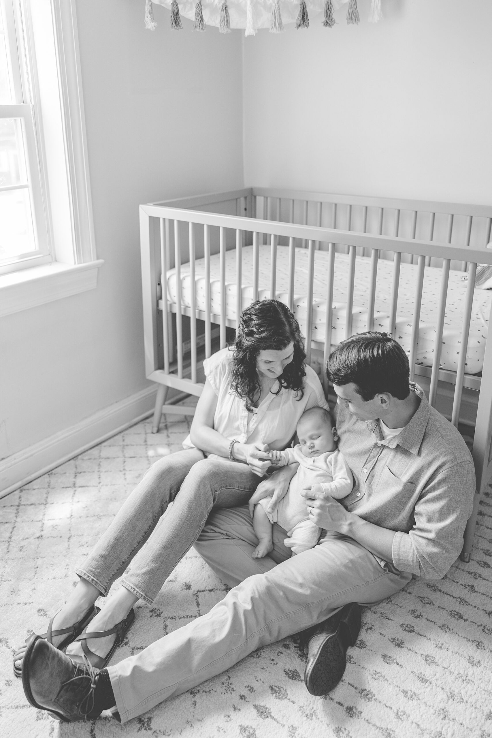 parents sit by the side of the crib holding their son