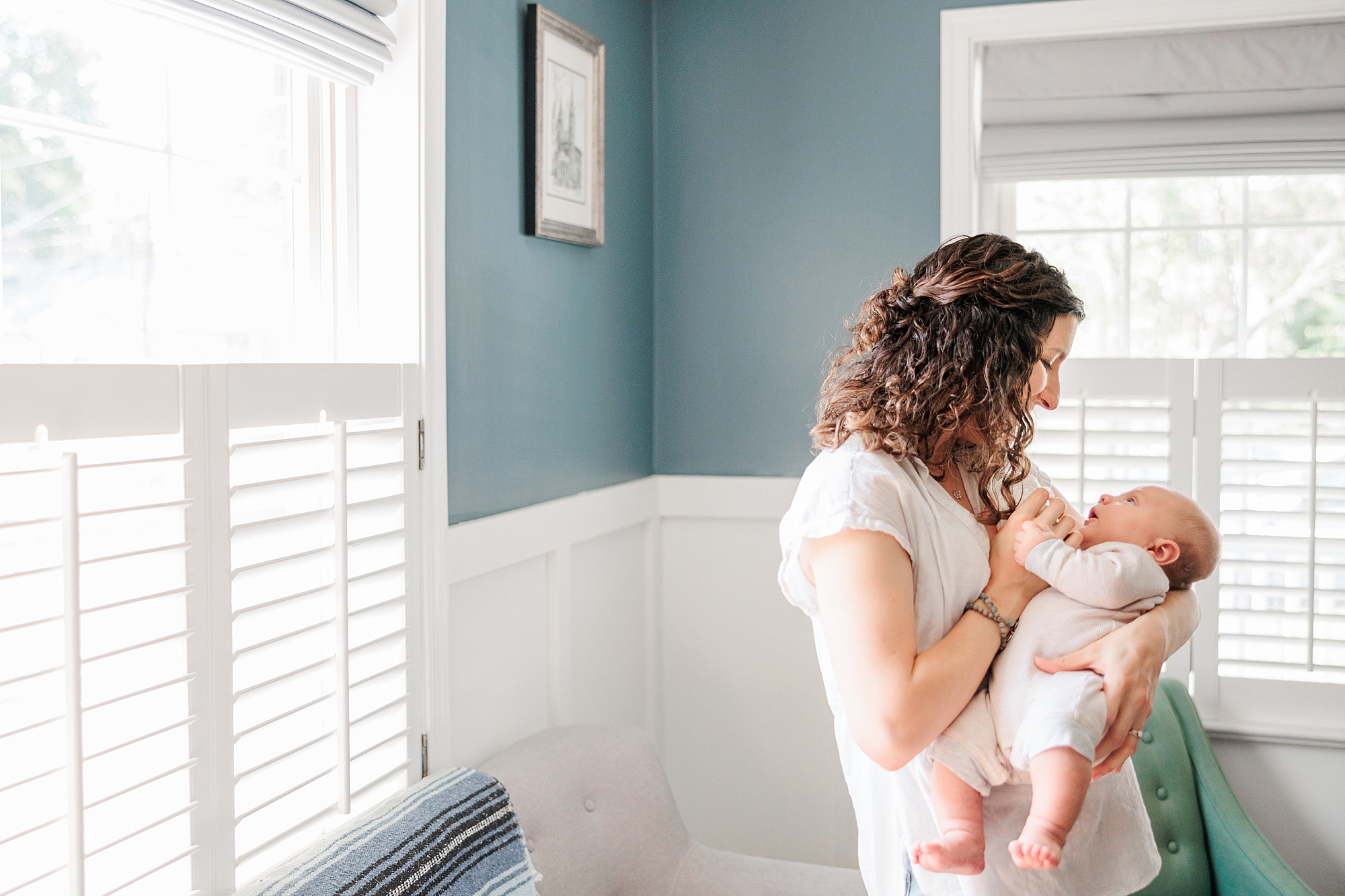 mom smiles down at son in her arms during newborn lifestyle photography session in Maryland 