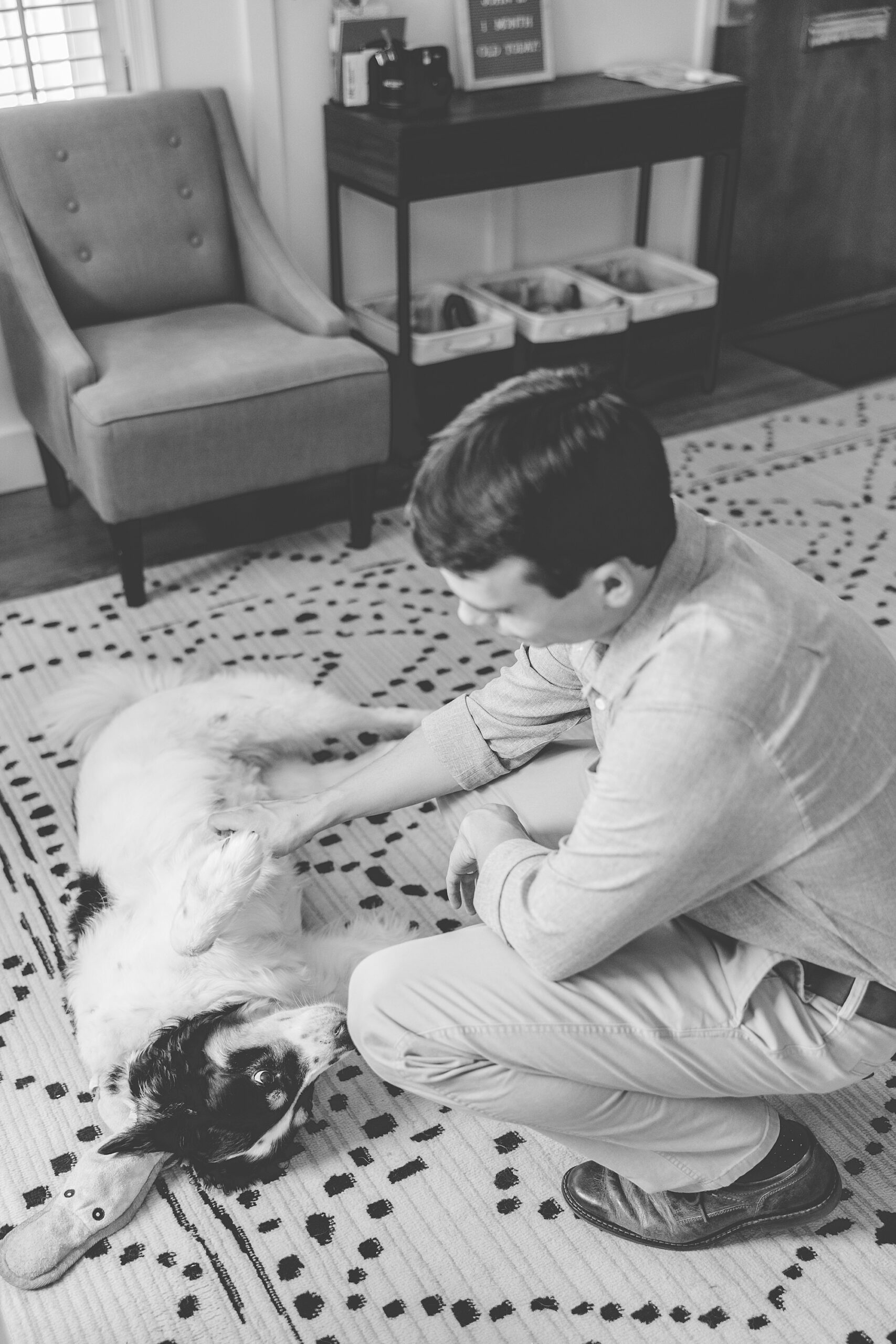 man plays with black and white dog on the floor of Maryland home 