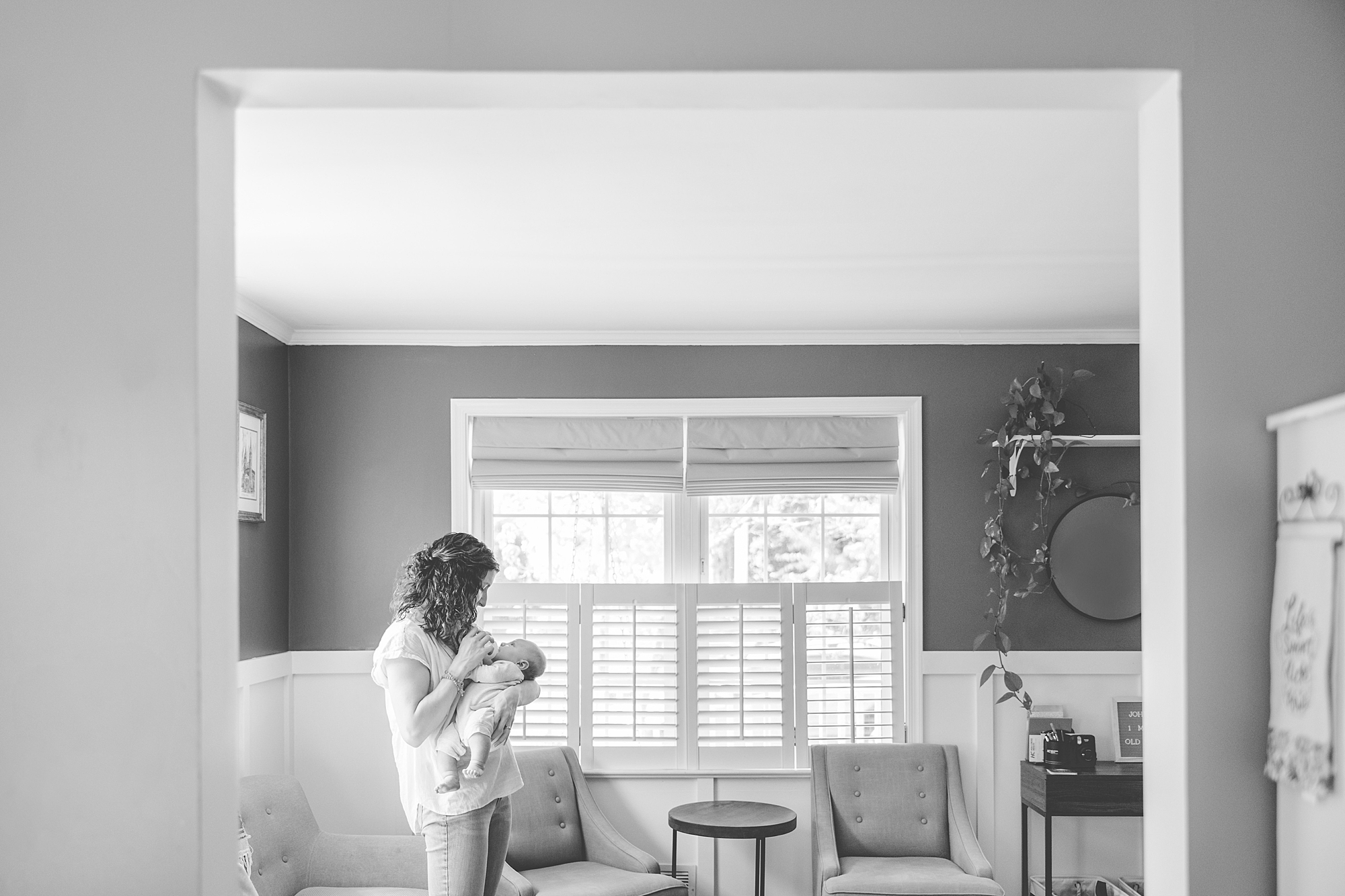 mom looks down at baby boy through doorway of home