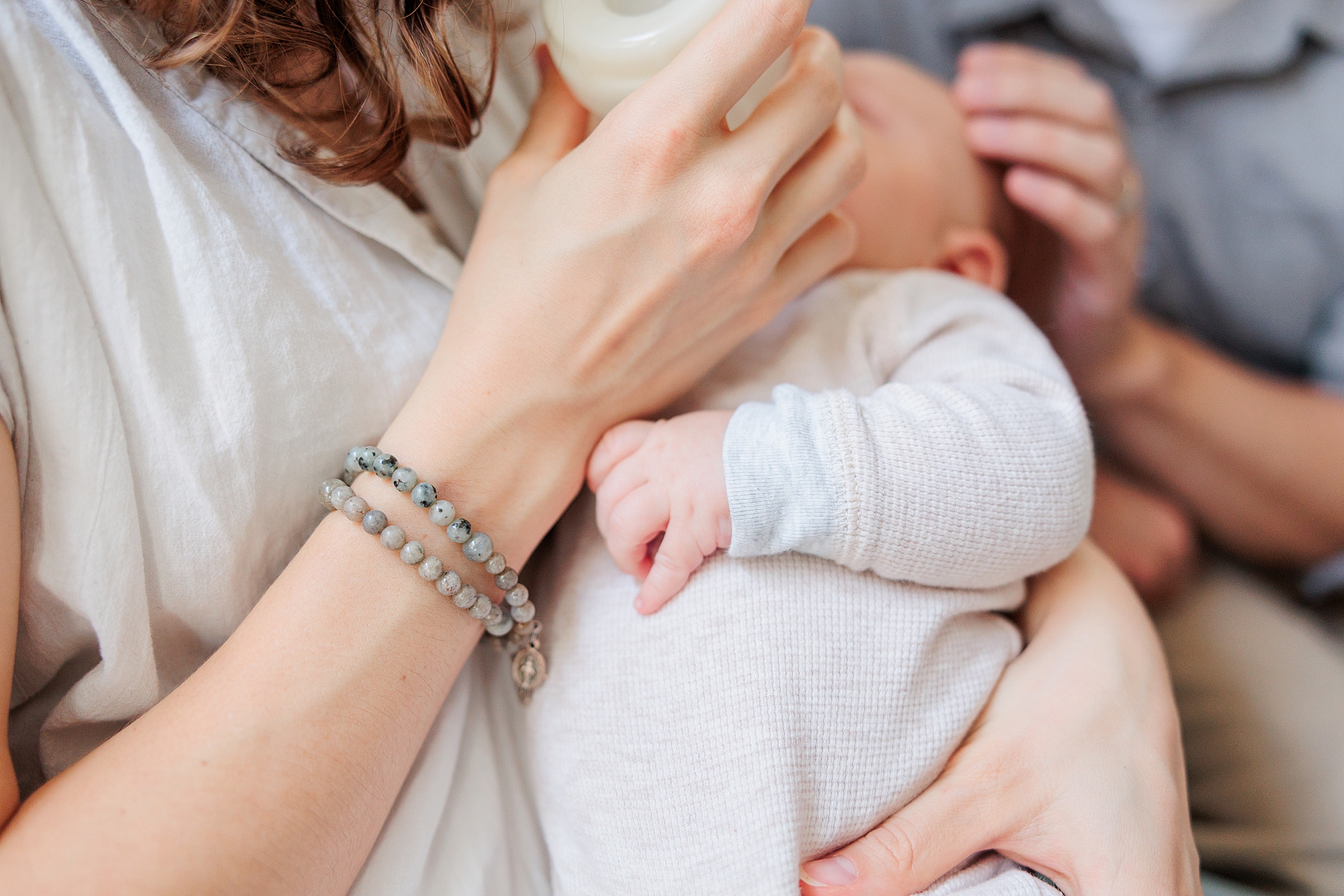 mom feeds baby with bottle during newborn lifestyle photography session in Maryland home