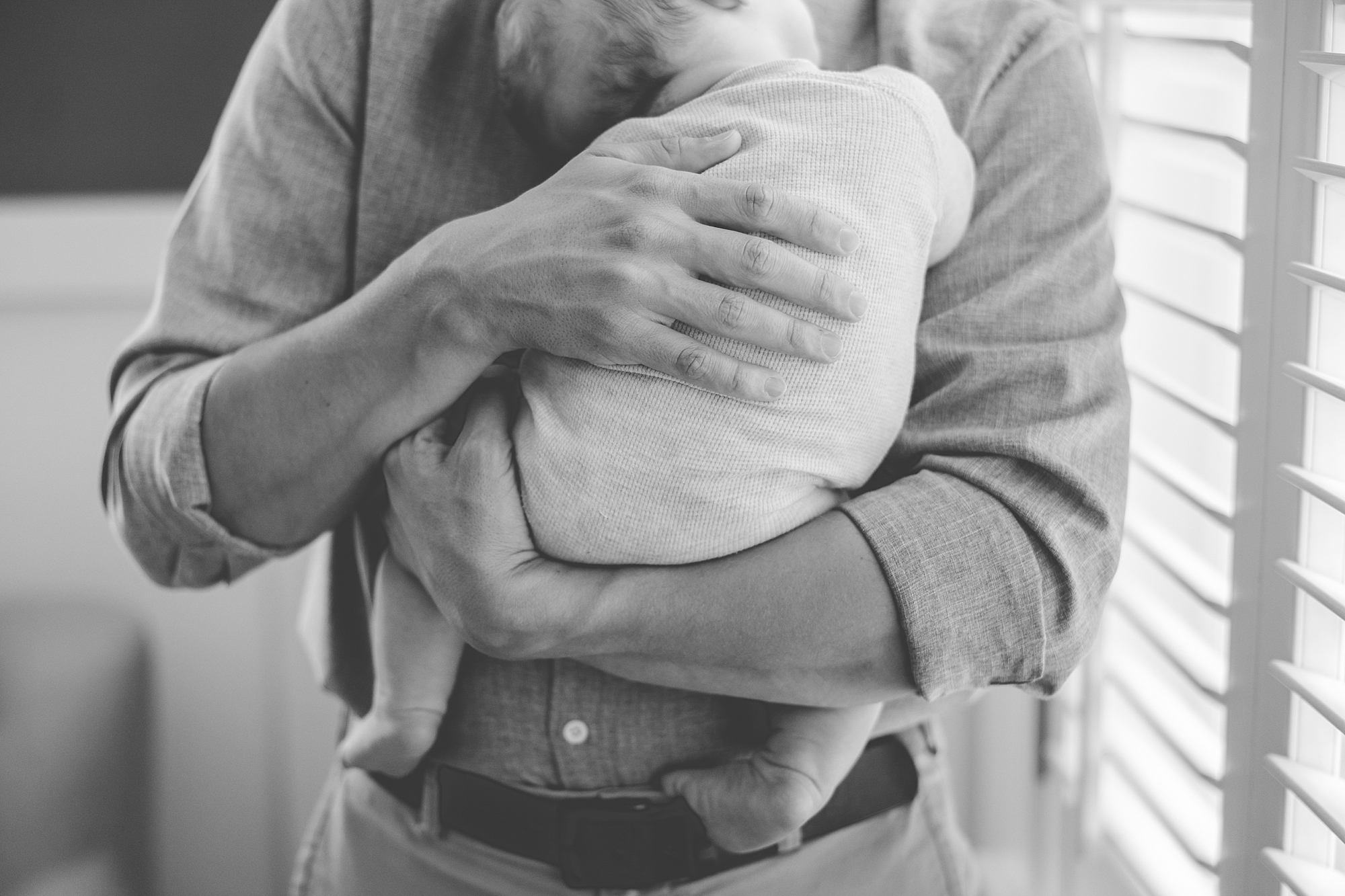 dad holds newborn son to his chest during photos at home 