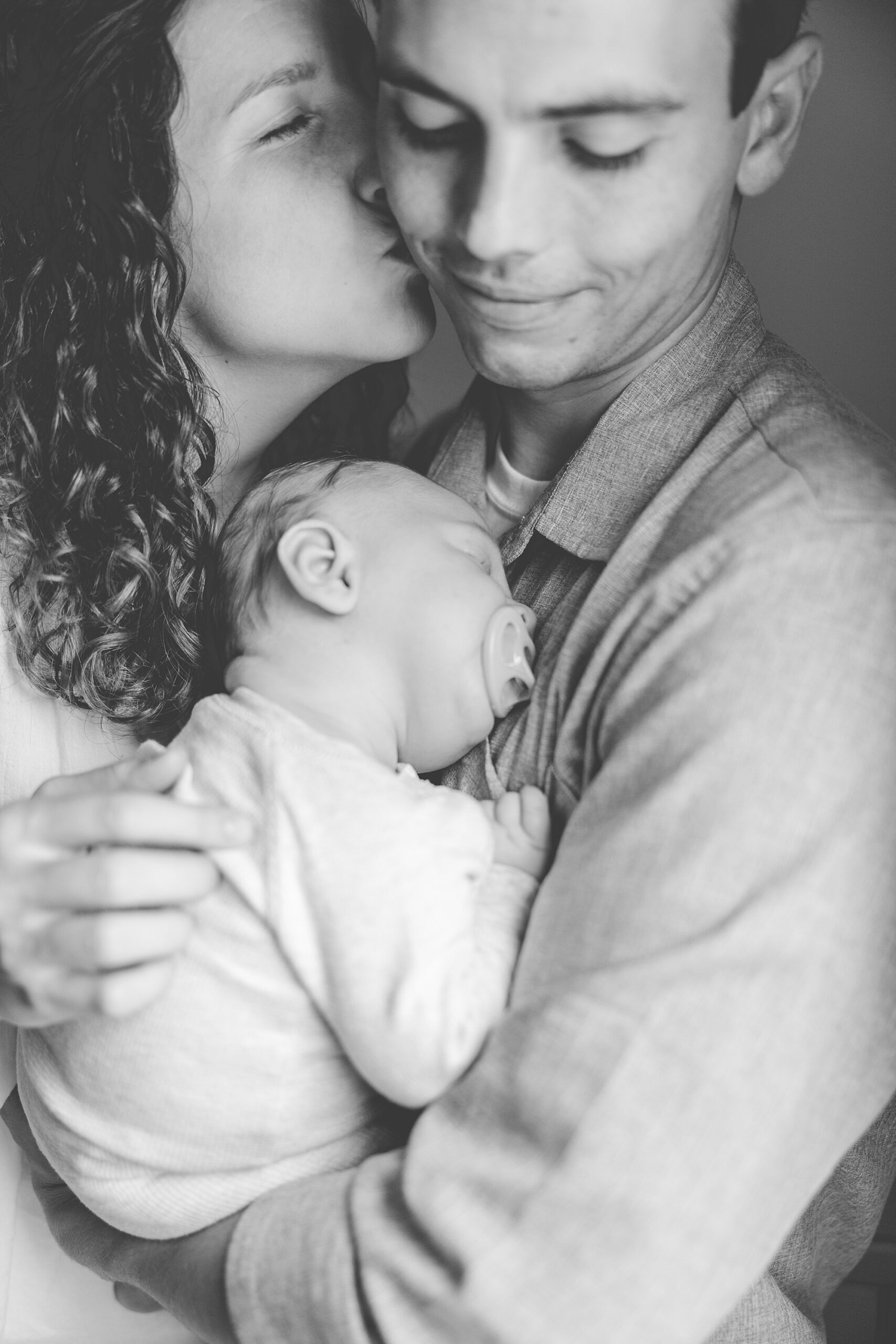 parents snuggle with son on their chest during Maryland family photos 