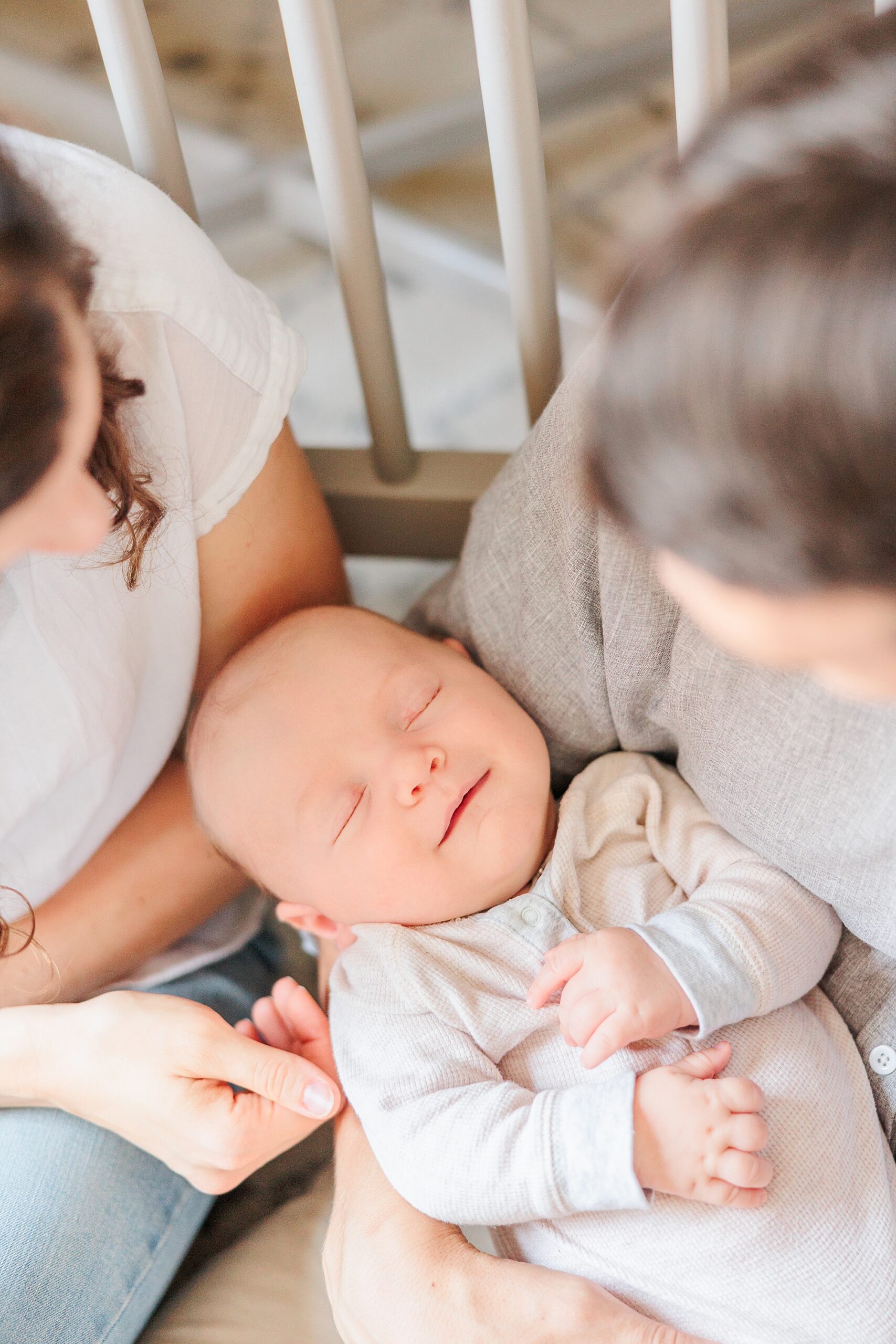 parents look down at son in their arms by crib