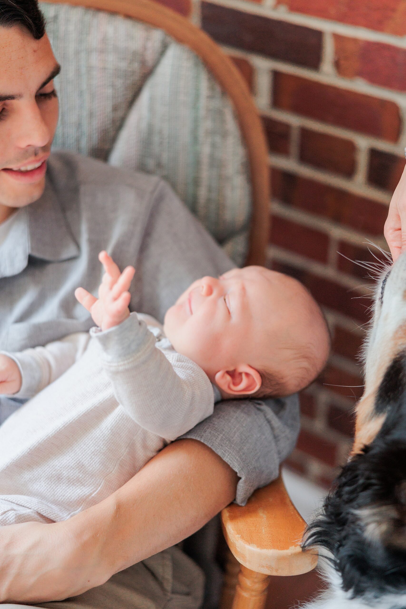 dad rocks with son in front of brick wall in Maryland home