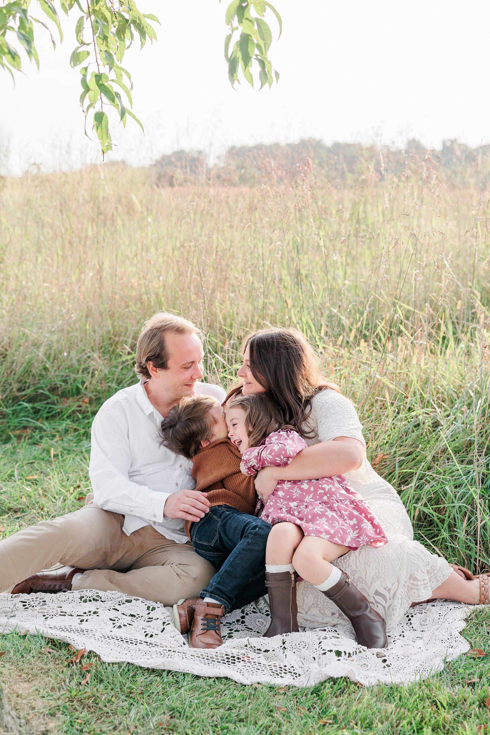 parents play with kids sitting on blanket during fall family photos