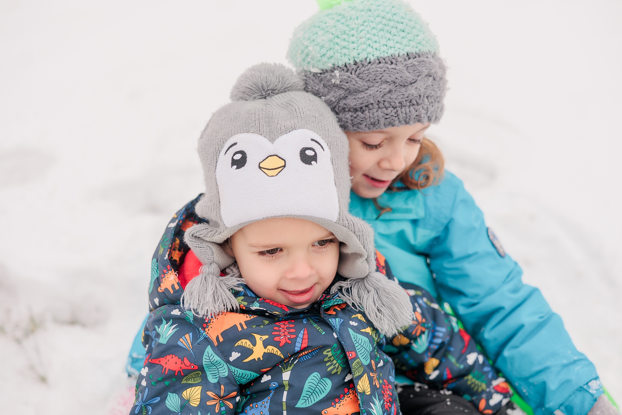 kids snuggle on sled during wintery snow day 