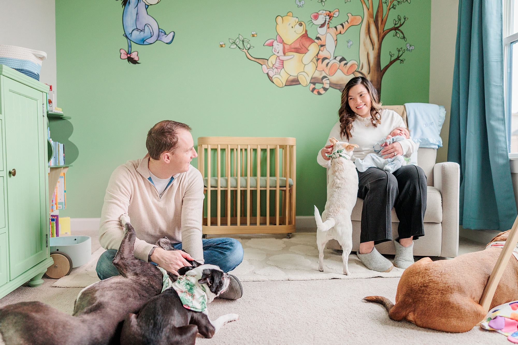 mom and dad sit with newborn baby and three dogs during cozy newborn session with Baltimore photographer