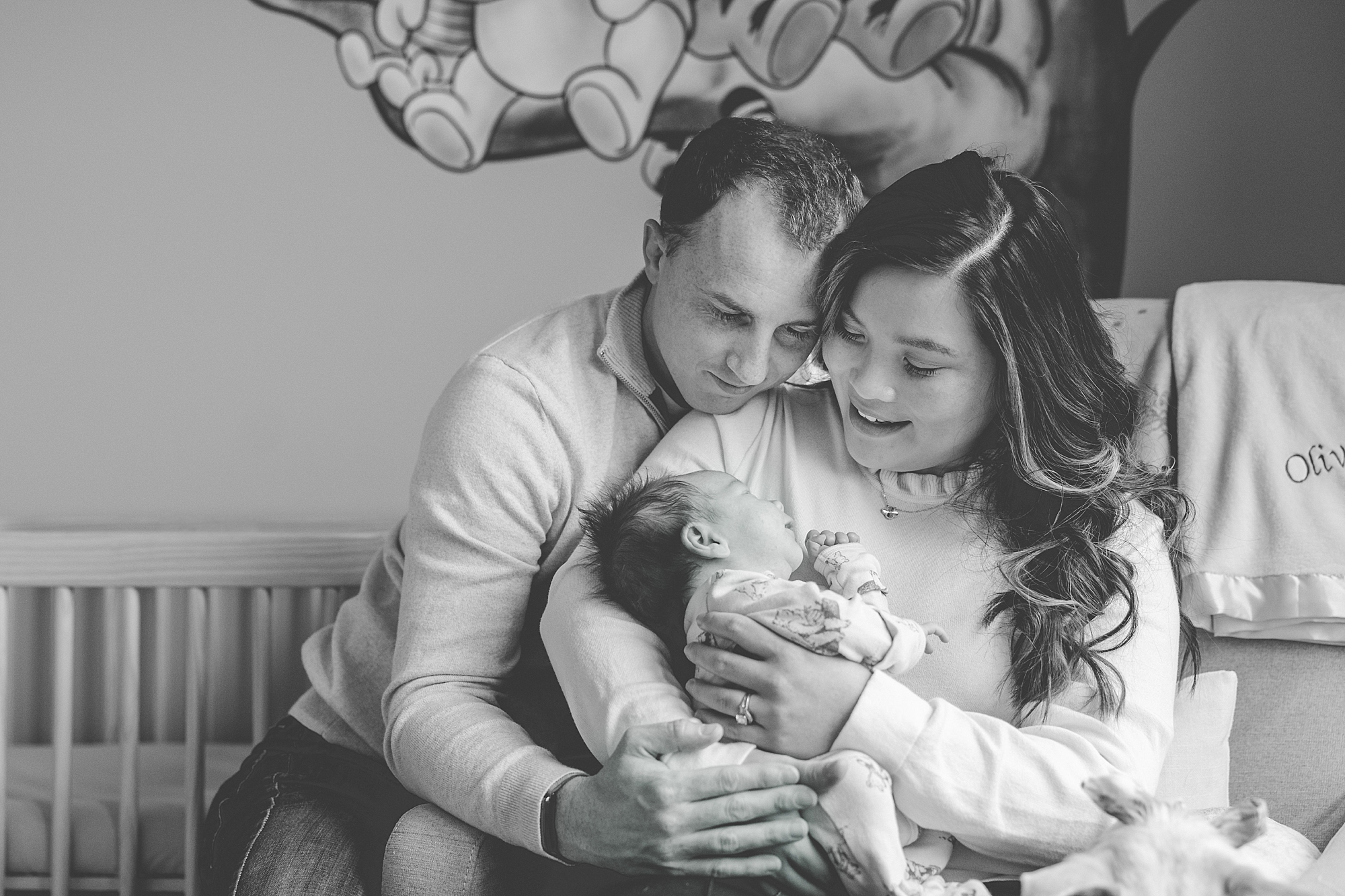 parents snuggle with baby in nursery during newborn session with Baltimore photographer