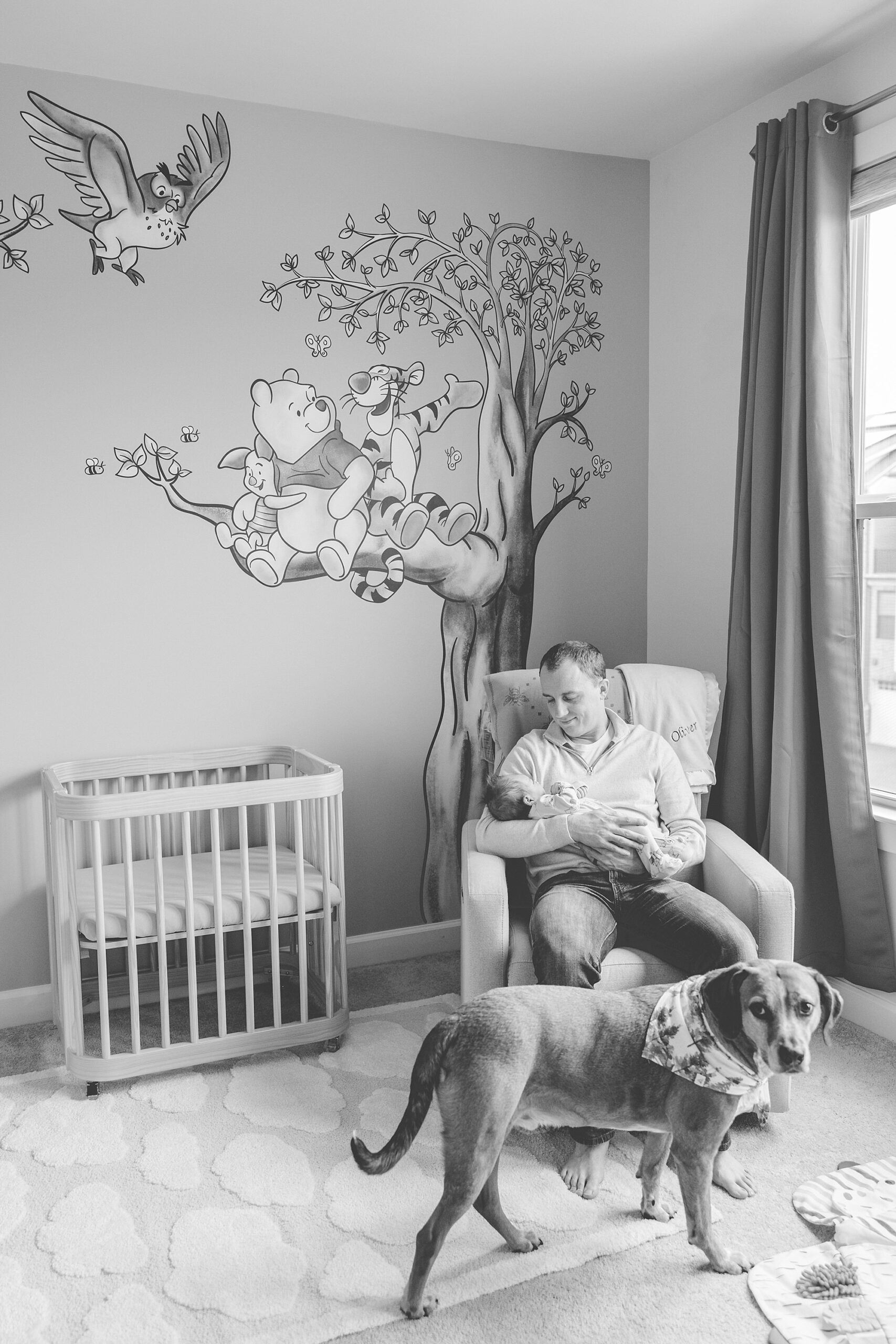 dad rocks in nursery with baby and dog at his feet