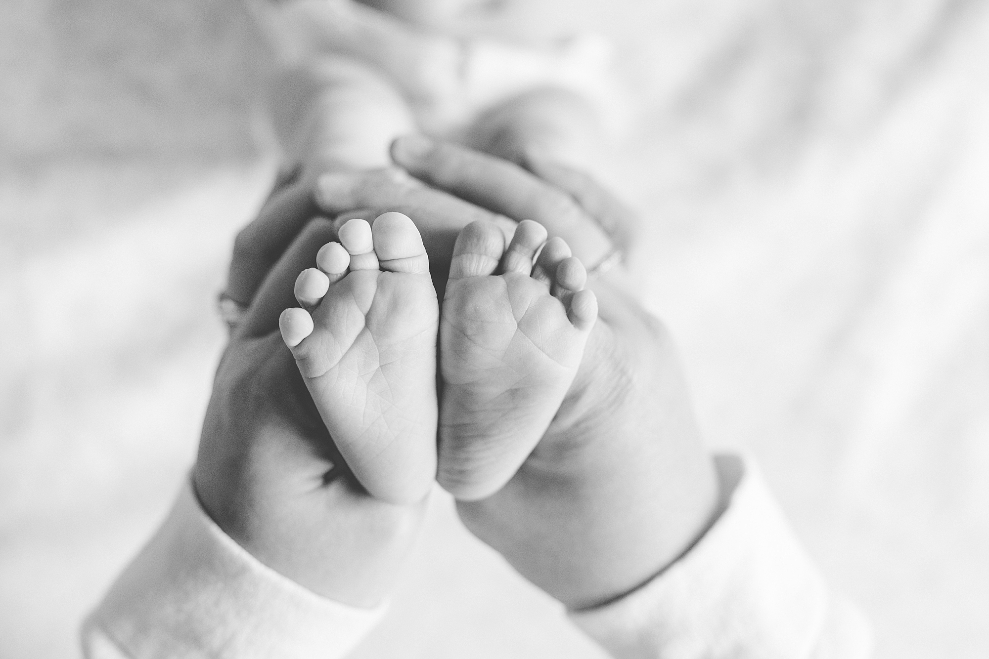 mom holds baby's feet laying on bed