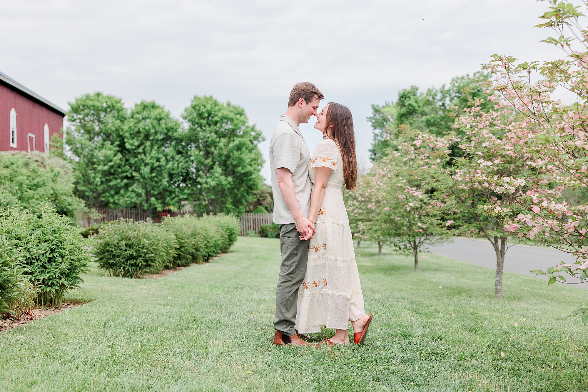 couple holds hands between rows of trees on Baltimore farm