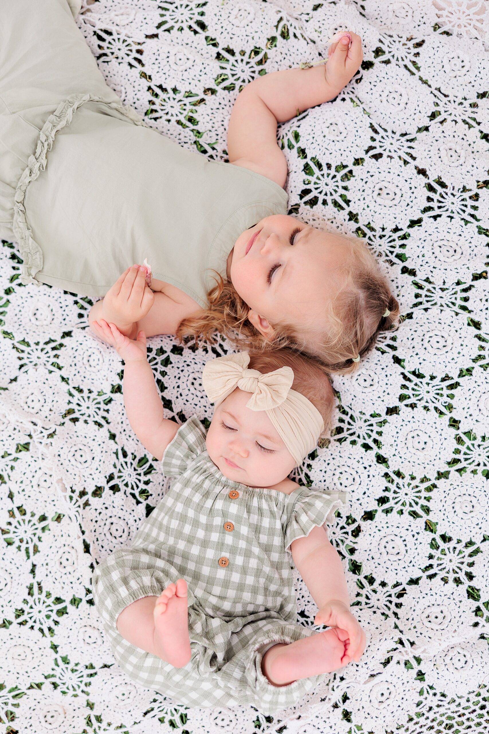 two sisters lay on white crochet blanket during Baltimore family photos