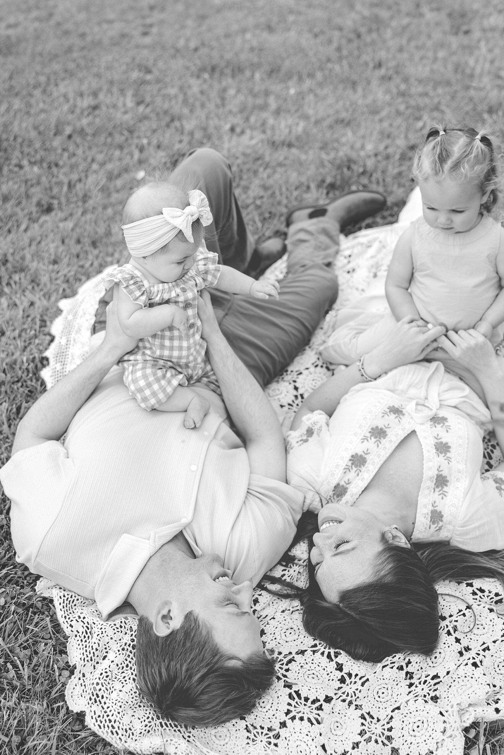 parents play with daughters on blanket during Baltimore lifestyle family session on farm