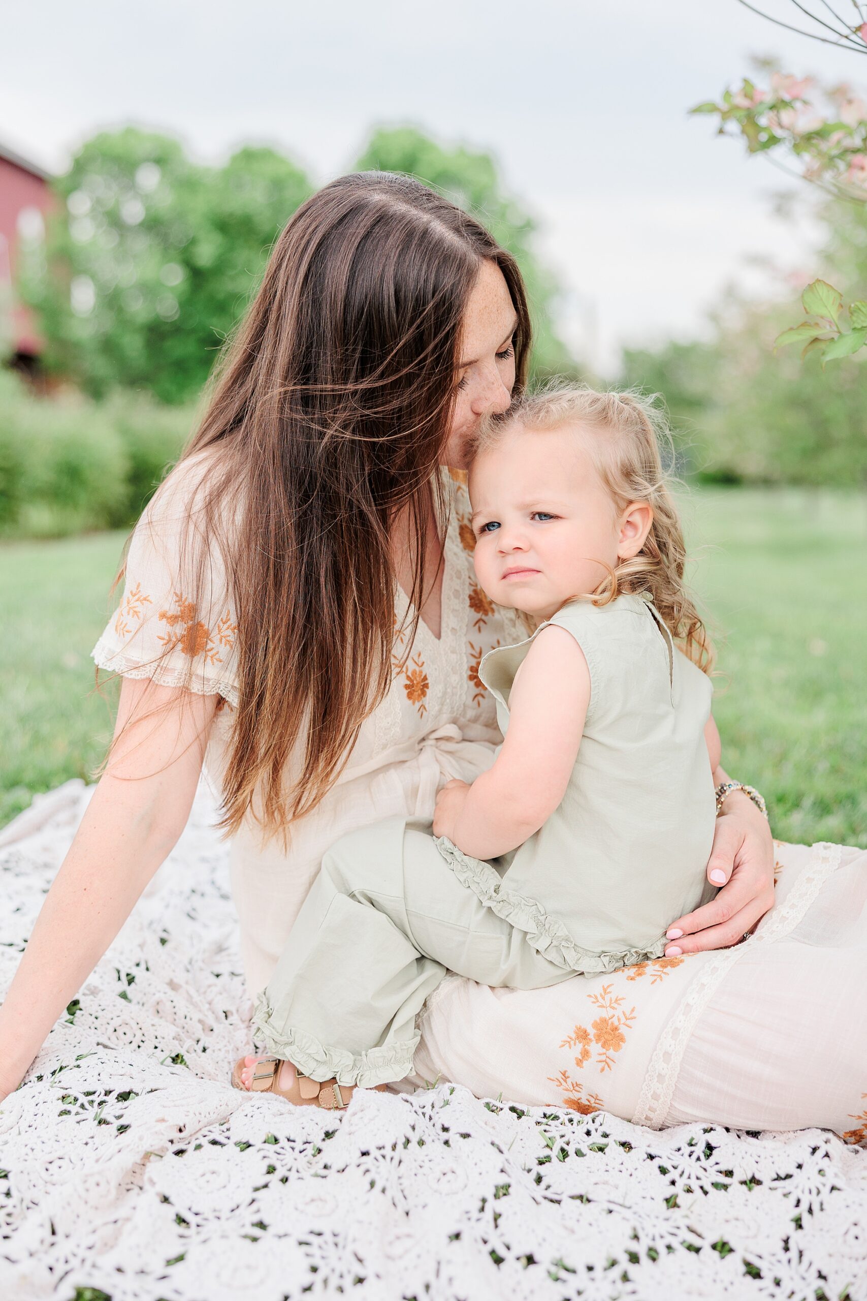 mom sits with toddler on lap during Baltimore lifestyle family session on farm