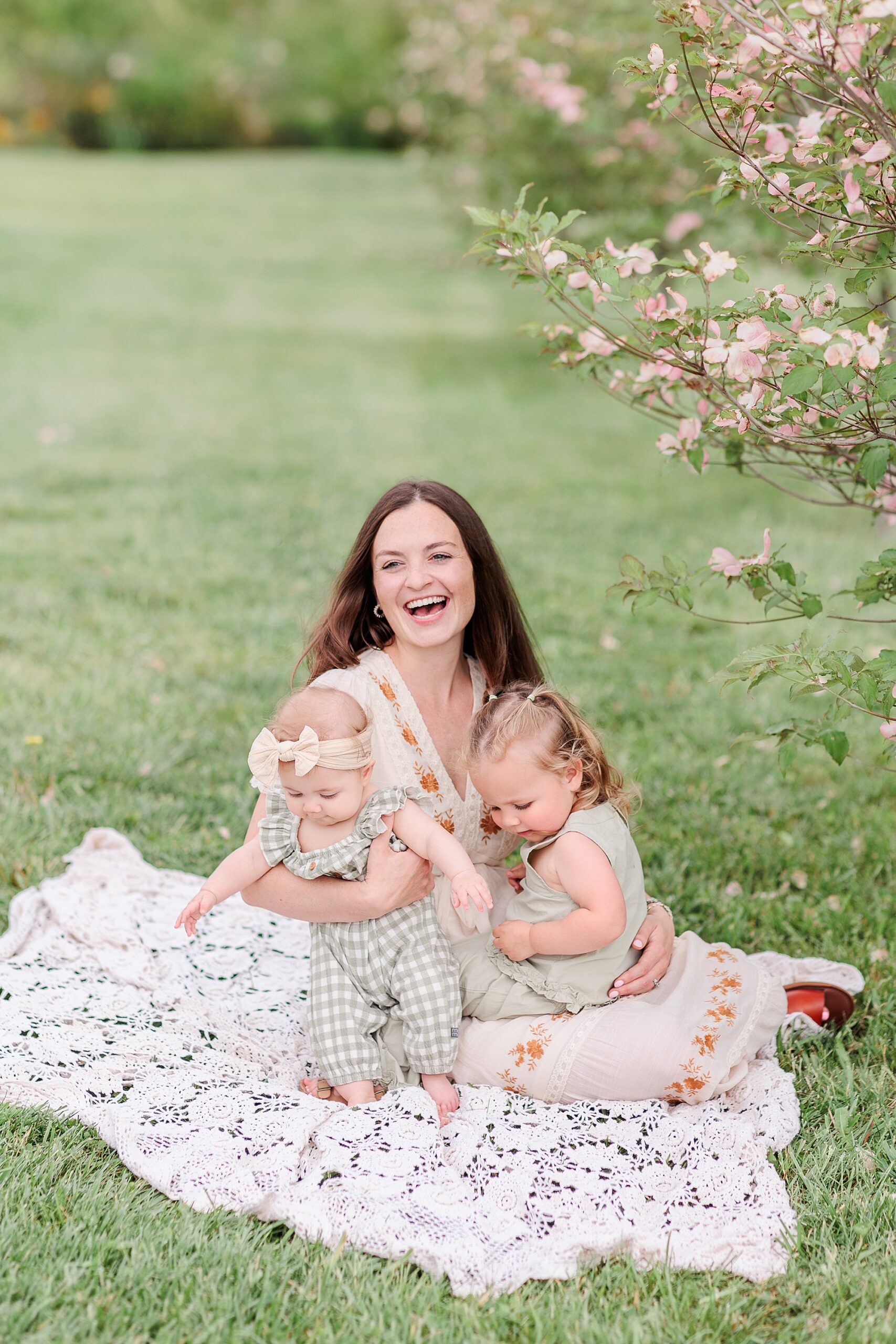 mom sits on blanket with two daughters 
