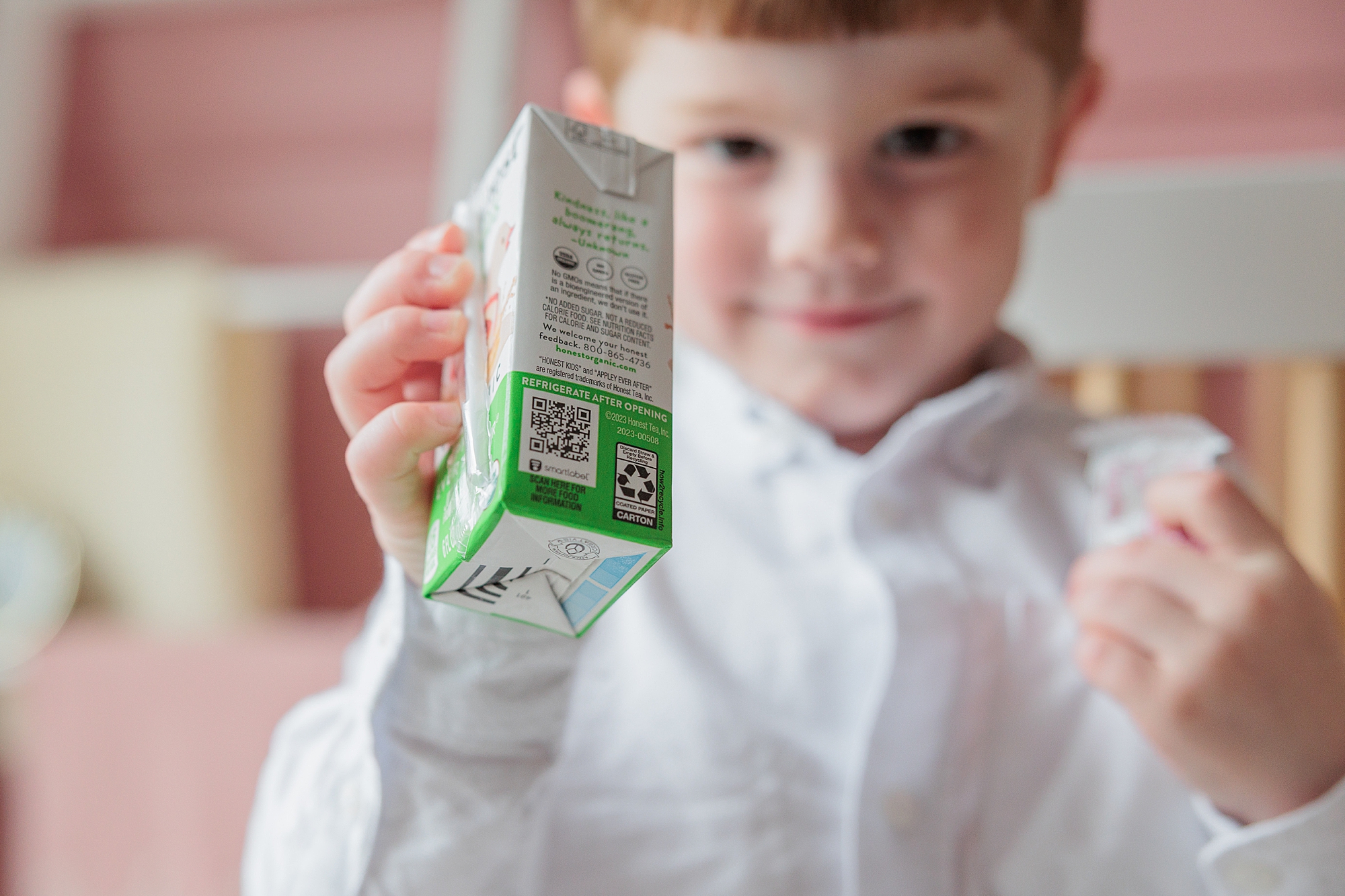 toddler holds juicebox towards camera during  photos at home