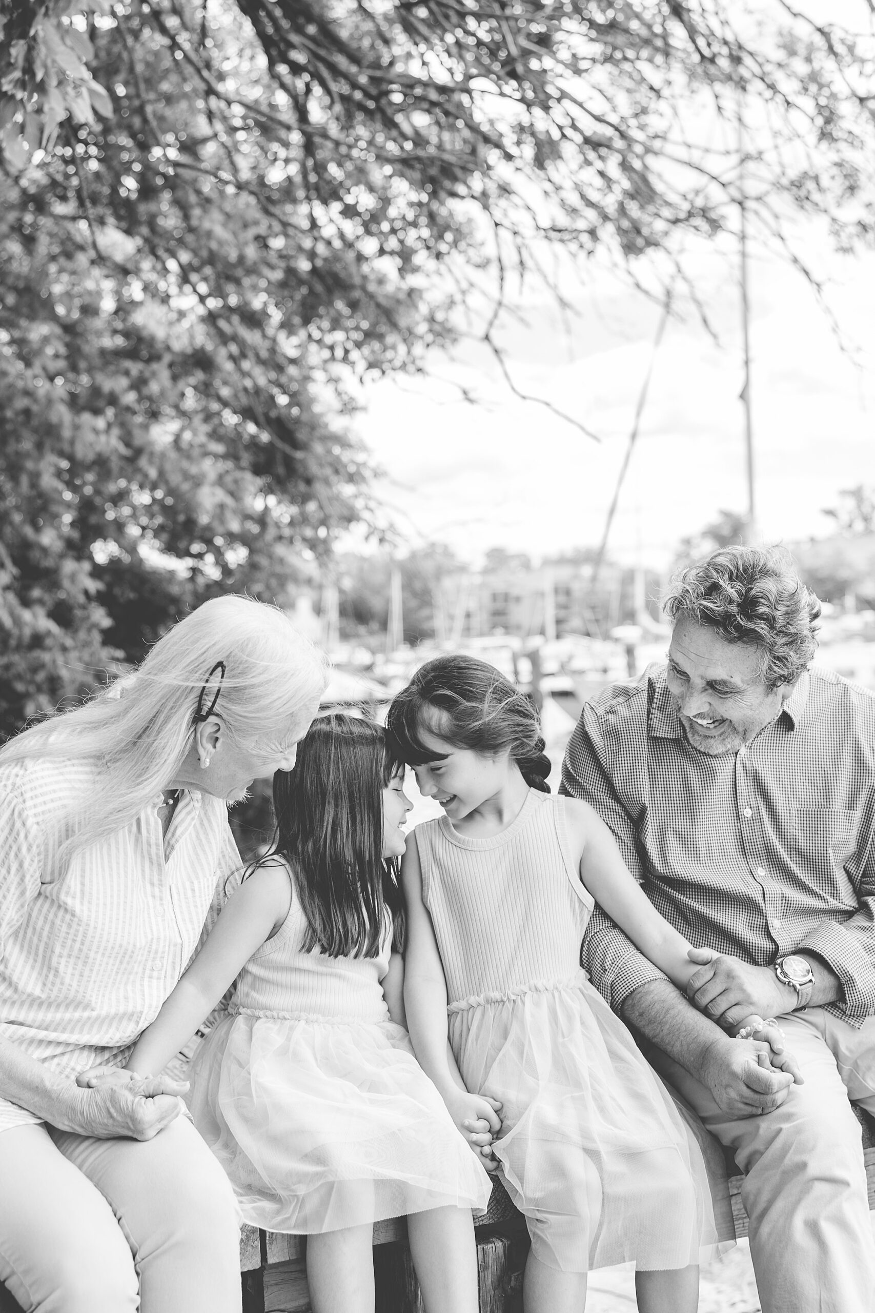 two sisters sit between grandparents on dock in Maryland 