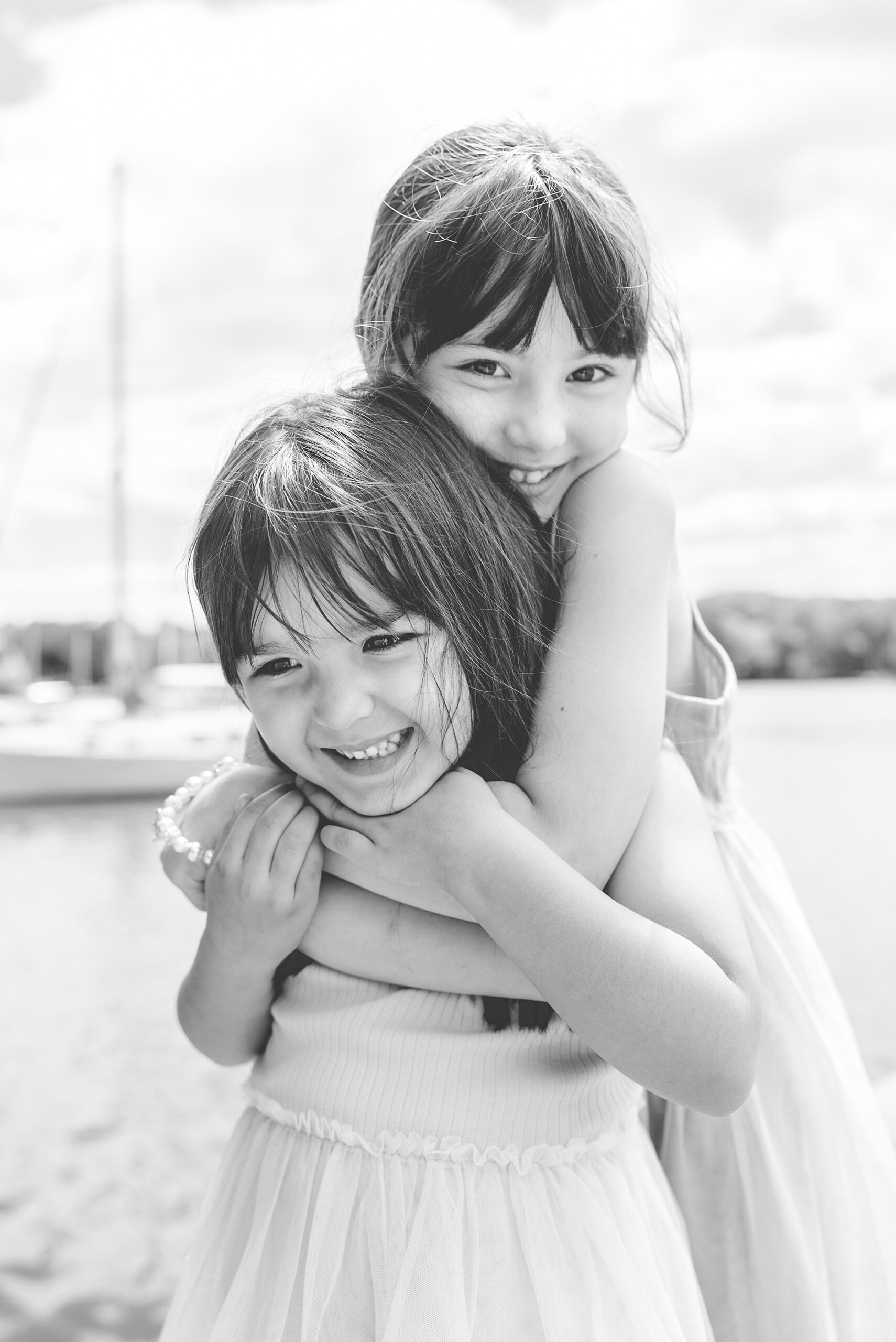 sisters hug on dock during family photos in Maryland 