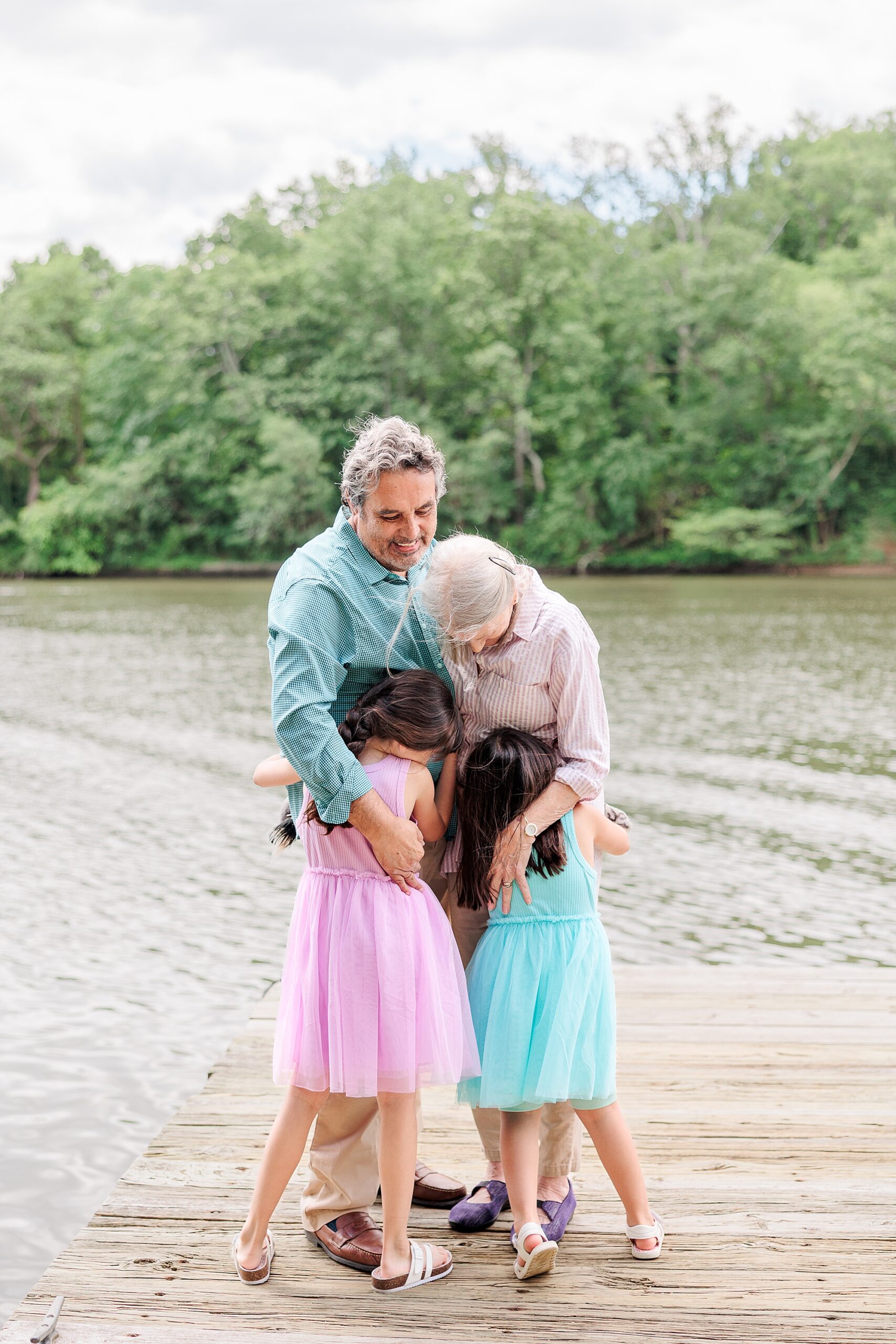 grandparents hug granddaughters on wooden dock