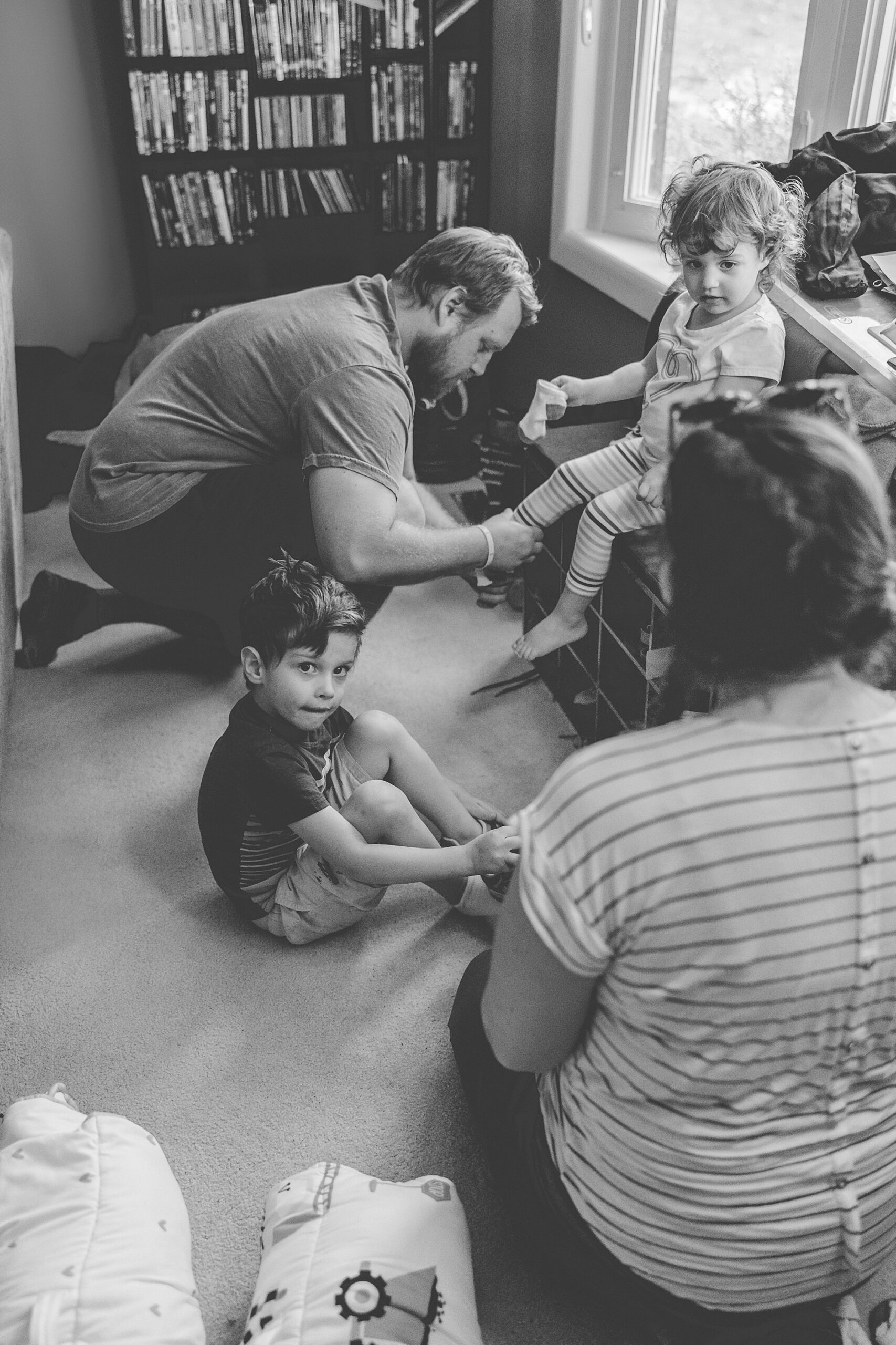 parents sit and help kids get shoes on during family photos