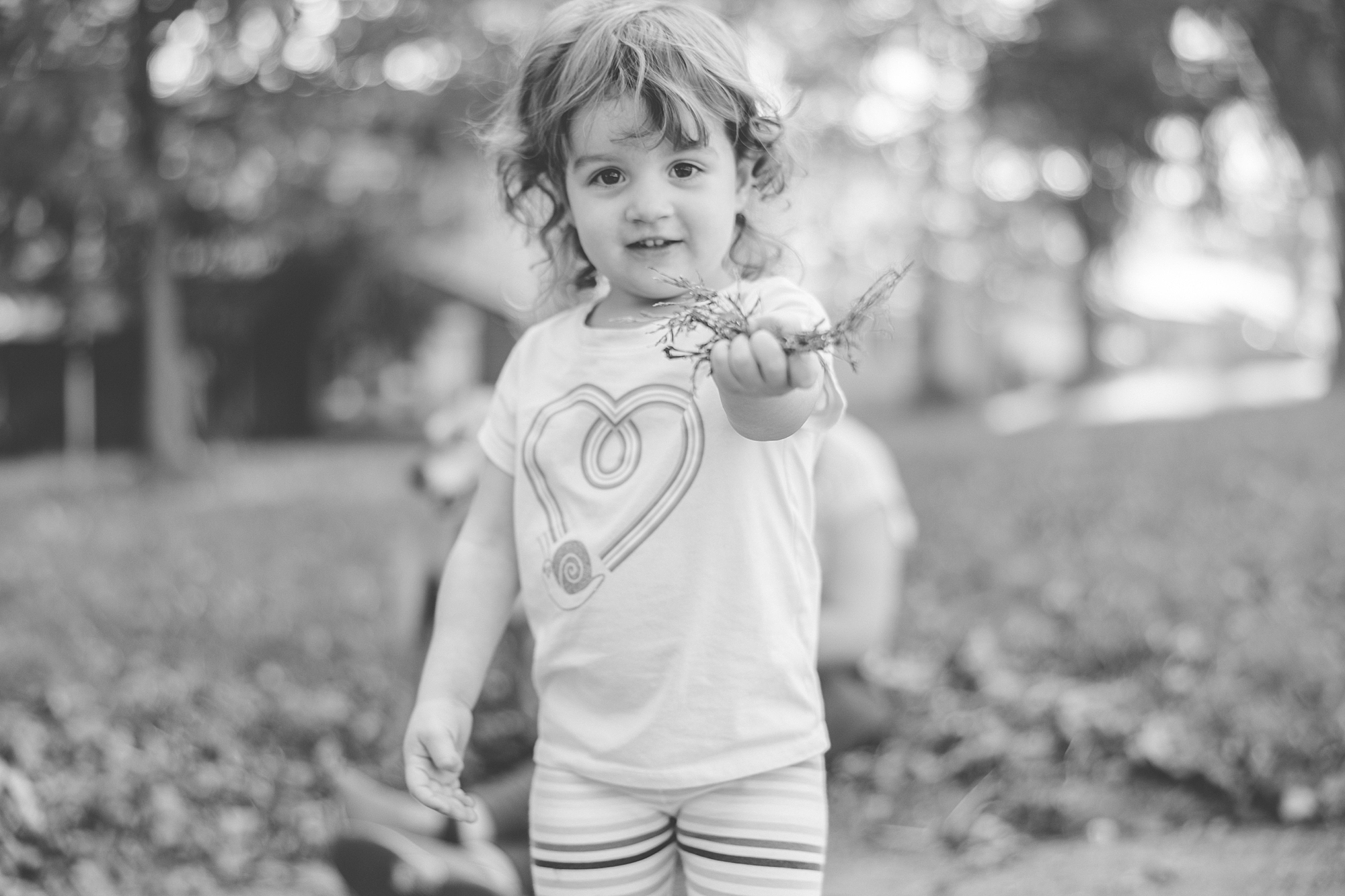 girl holds out leaves during Maryland documentary family photos in backyard 