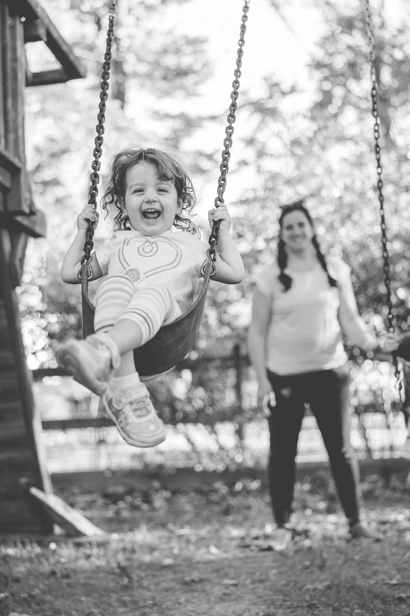 girl laughs on swing while mom pushes her