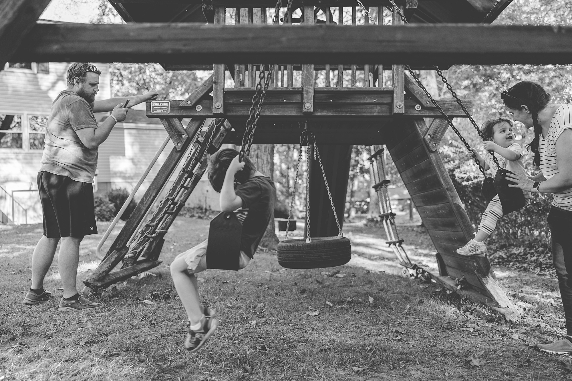 kids play on swing set in backyard with parents 