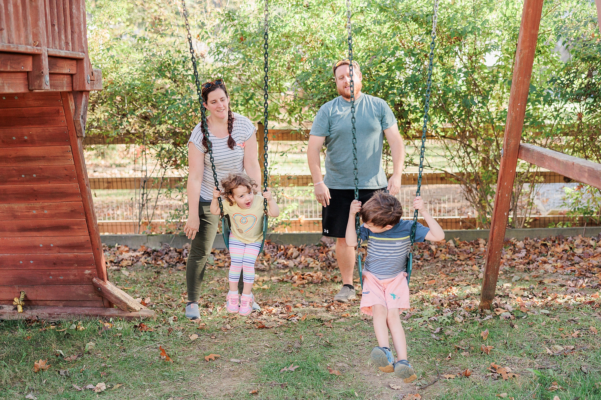 parents play with two children on swing set in Maryland